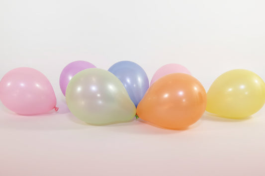 Colorful balloons on a wooden surface with a white wall background