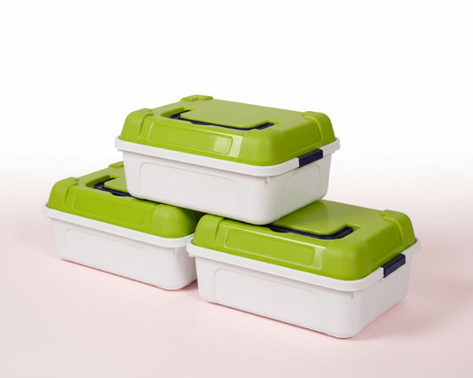 Stack of green and white storage containers on a wooden surface with a white wall background.