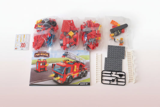 Toy fire truck set with packaging and accessories on a wooden surface