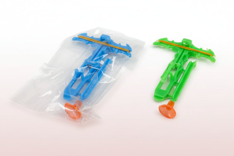 Two toy airplanes, one blue and one green, on a wooden surface with a white background.