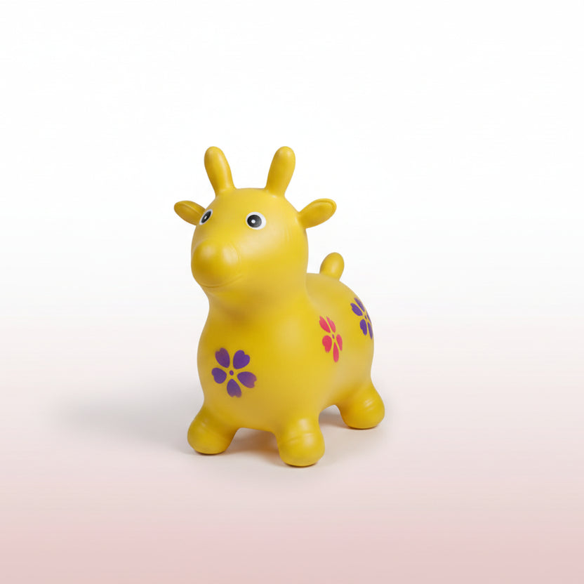 Yellow toy giraffe with a purple flower on a cardboard box surrounded by other toys.