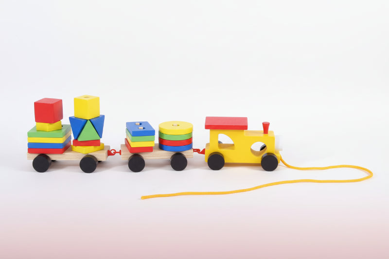 Colorful wooden toy train set on a wooden surface with a plain background