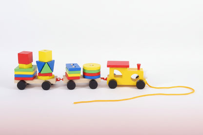 Colorful wooden toy train set on a wooden surface with a plain background