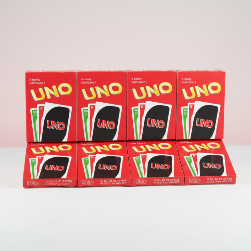 Multiple boxes of UNO card game on a wooden surface with a white background