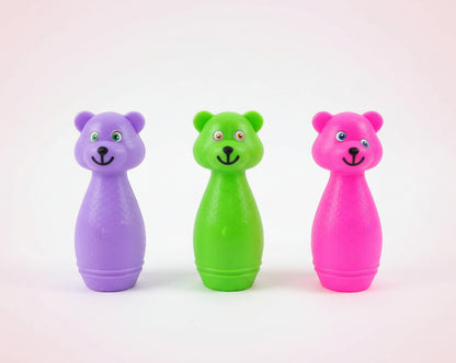 Three colorful bear-shaped toys in a clear bag on a wooden surface.