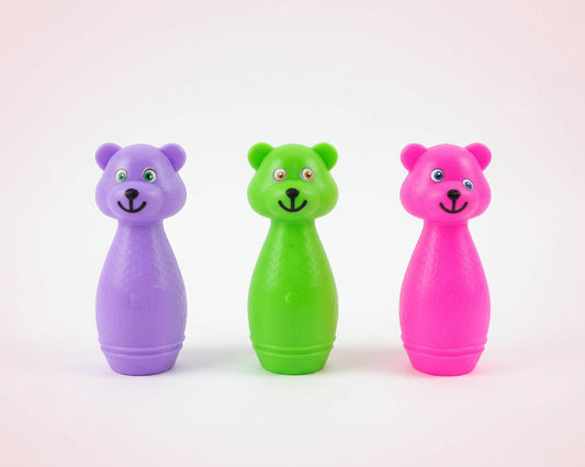 Three colorful bear-shaped toys in a clear bag on a wooden surface.