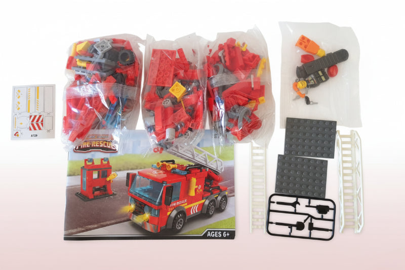 Toy fire truck set with packaging and accessories on a wooden surface