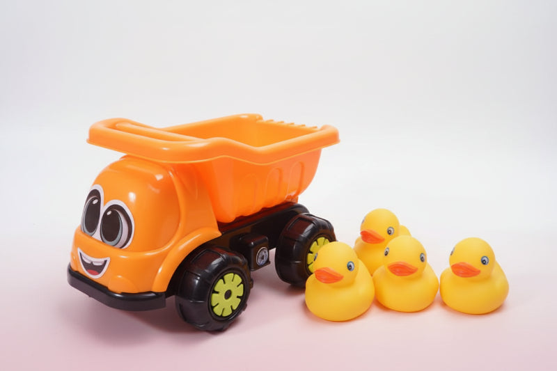Orange toy dump truck with yellow rubber ducks on a wooden surface