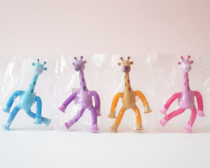 Four colorful giraffe toys in clear packaging on a wooden surface.