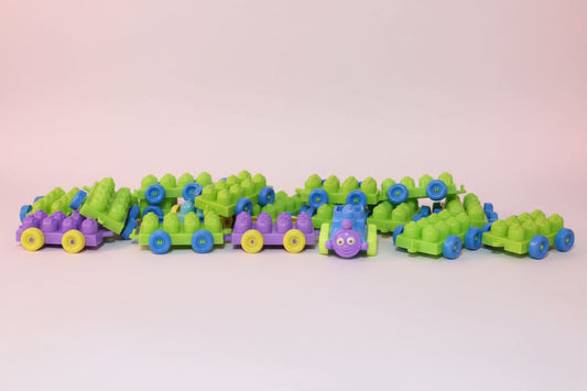 Row of colorful toy trains on a wooden surface with a white wall background