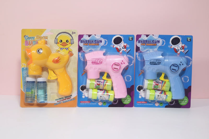 Three bubble gun toys in their packaging on a wooden surface with a beige wall background.