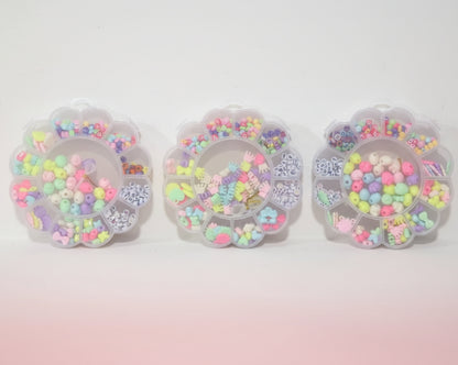 Three clear containers filled with colorful beads on a wooden surface.