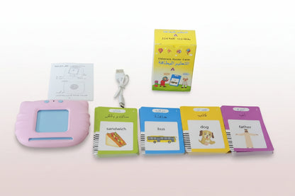 Educational toys and materials including a pink electronic device, flashcards, and a box on a wooden surface.