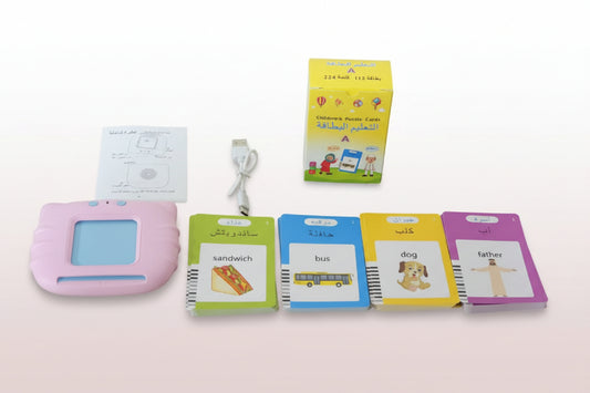 Educational toys and materials including a pink electronic device, flashcards, and a box on a wooden surface.