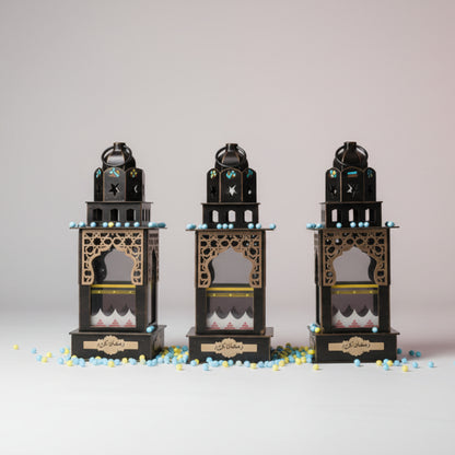Three decorative lanterns in clear plastic packaging on a wooden surface.