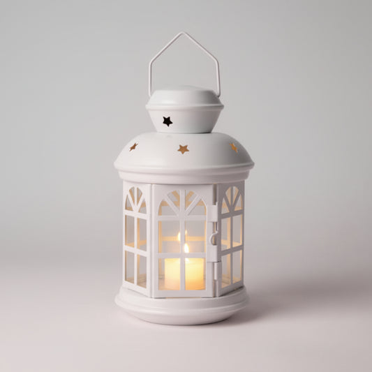 White lantern with a warm glow on a wooden surface against a beige wall