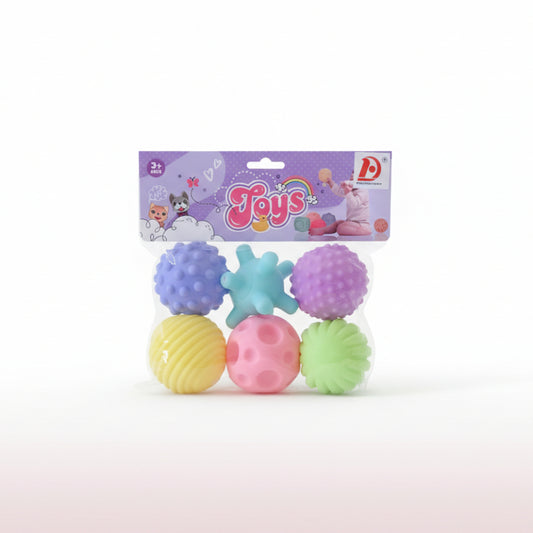 Set of colorful textured balls in a package with 'Toys' branding on a wooden surface.