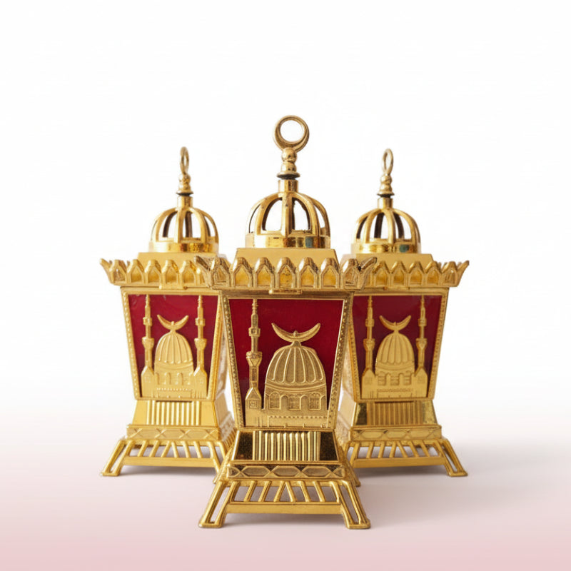 Three ornate gold and red lantern-like structures in clear plastic packaging on a wooden surface.
