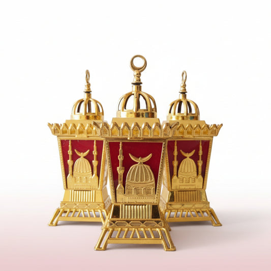 Three ornate gold and red lantern-like structures in clear plastic packaging on a wooden surface.