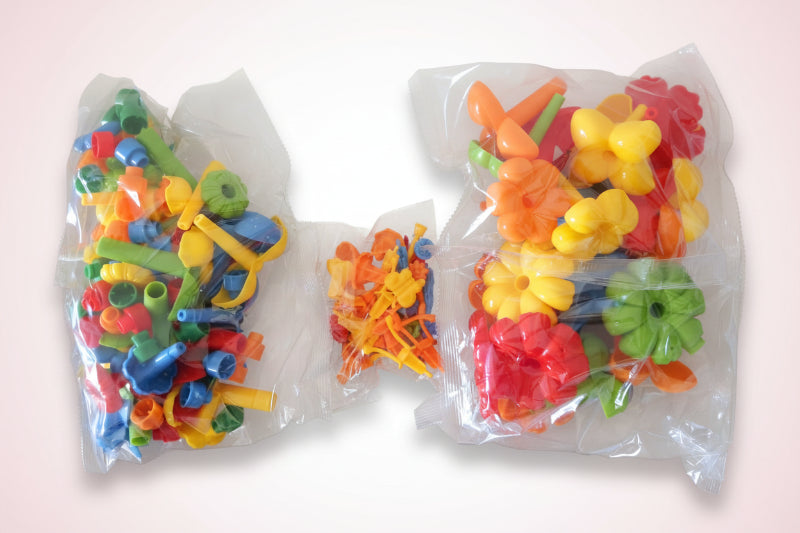 Colorful plastic building blocks in clear bags on a wooden surface