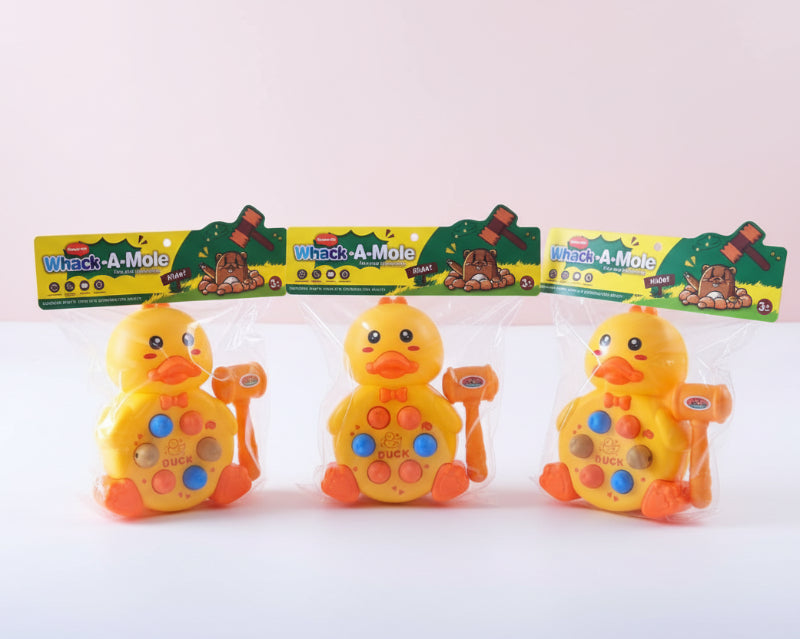 Three rubber duck toys in packaging with 'Whack-A-Mole' branding on a wooden surface.