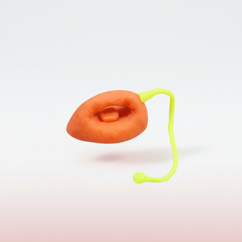 Orange object with a green string on a wooden surface