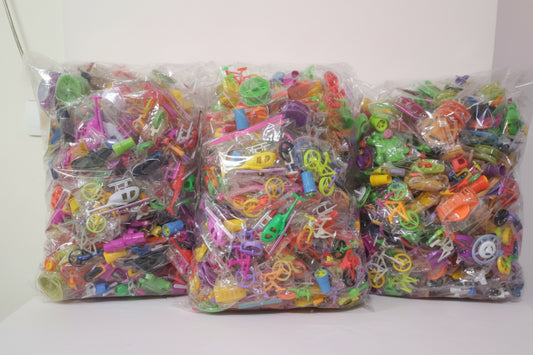 Three bags of colorful plastic toys on a wooden surface with a white background