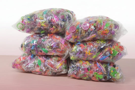 Multiple bags of colorful rubber bands on a wooden surface with a white background