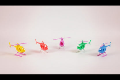 Five colorful toy helicopters on a wooden surface with a plain background