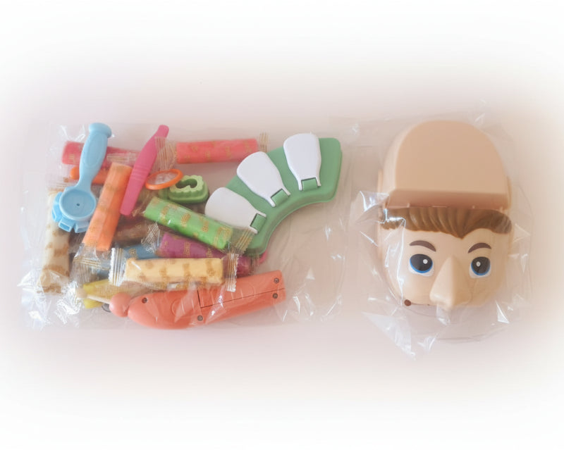 Toy figure parts including a head and various accessories on a wooden surface.