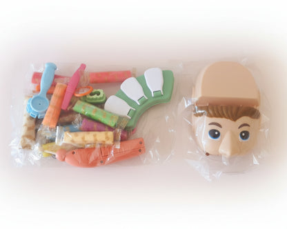 Toy figure parts including a head and various accessories on a wooden surface.