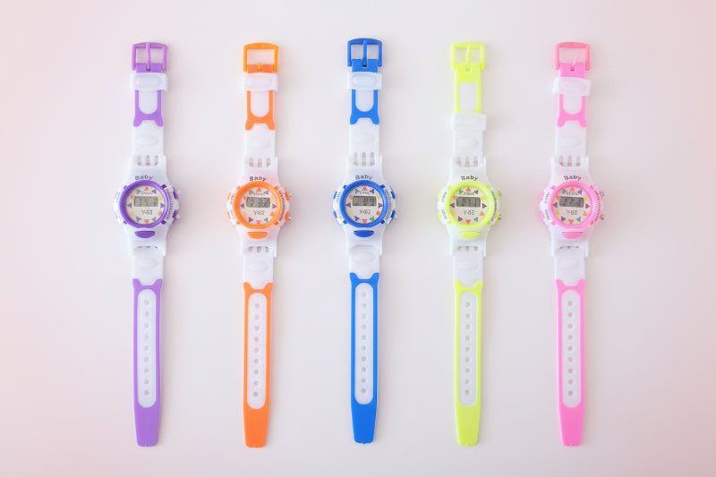 Five colorful digital watches with different colored straps on a wooden surface.