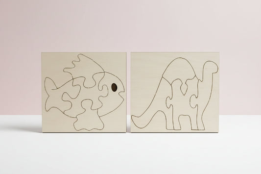 Two wooden puzzle pieces shaped like a fish and a dinosaur on a dark surface.