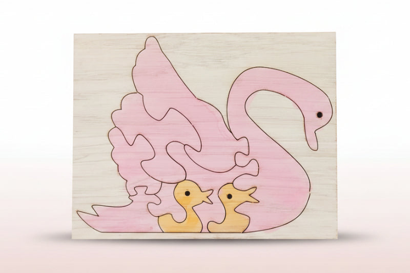 Wooden puzzle with pink swan and yellow ducklings on a white background