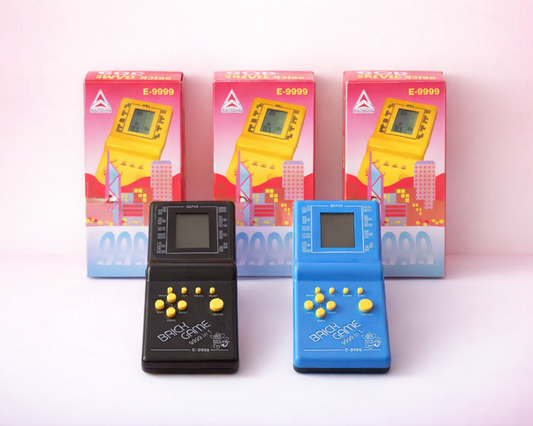 Two vintage handheld gaming devices, one black and one blue, with their packaging in the background.
